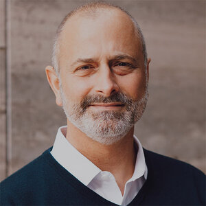 Headshot of John Hecklinger, president and CEO of Global Fund for Children, in a white shirt and navy blue sweater. Headshot of John Hecklinger, president and CEO of Global Fund for Children, in a white shirt and navy blue sweater.