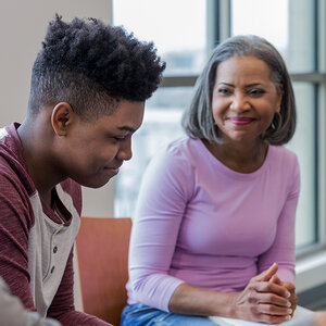 An African American teenager is talking to his smiling grandmother. An African American teenager is talking to his smiling grandmother.