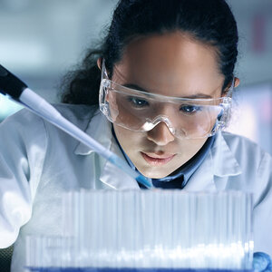 A female scientist wearing safety glasses working in her lab. A female scientist wearing safety glasses working in her lab.
