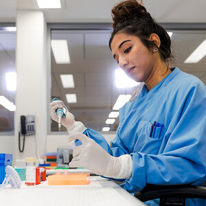 A female scientist in a lab prepares a sample for a diagnostic test. A female scientist in a lab prepares a sample for a diagnostic test.