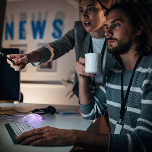 Two journalists reviewing a story on the computer. Two journalists reviewing a story on the computer.