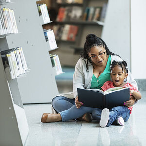 A child and woman reading in a library. A child and woman reading in a library.