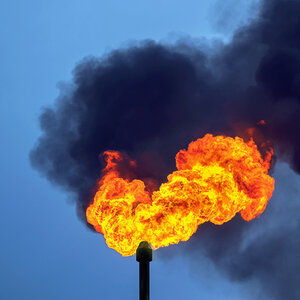 A plume of black smoke and flame spews from a oil refinery smokestack. A plume of black smoke and flame spews from a oil refinery smokestack.
