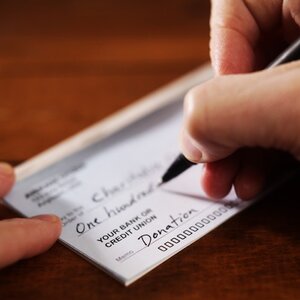 Hand with a pen writing a check.