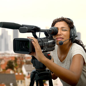 A Black woman behind the camera films for a movie or television. A Black woman behind the camera films for a movie or television.