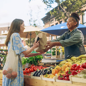 A woman getting food at a farmers market. A woman getting food at a farmers market.