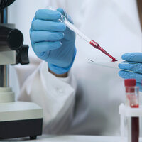 A researcher with a blood sample. A researcher with a blood sample.