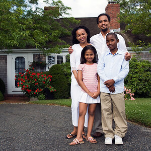An African American family of four standing in front of their house.