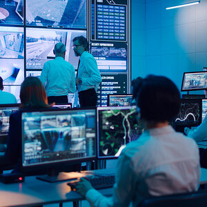 A security command center with an array of screens showing data and video images. A security command center with an array of screens showing data and video images.