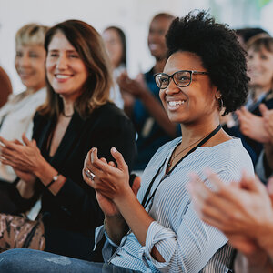 A group of people at a presentation clapping their hands.