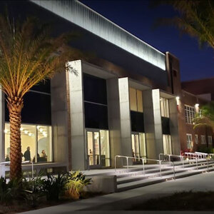 The columned façade of a modern art museum surrounded by palm trees at night.