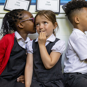 Elementary school kids lined up whispering to each other.