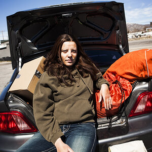 A homeless woman sitting in the open trunk of the car where she's living. A homeless woman sitting in the open trunk of the car where she's living.