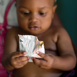 A baby holding a nutritional package. A baby holding a nutritional package.