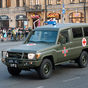 A military ambulance passing onlookers during a parade.