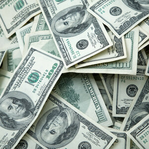 An image of $100 bills spread around in a pile.