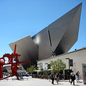 The exterior of a modern art museum with a red sculpture in the foreground beneath a blue sky – the Denver Art Museum.