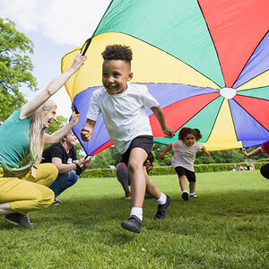 Children and adults playing with a colorful parachute in a grassy area. Children and adults playing with a colorful parachute in a grassy area.