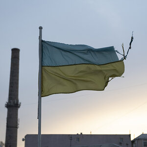 A battered Ukrainian flag flies over a building in Ukraine.