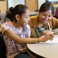 A teacher helps a student with her assignment. A teacher helps a student with her assignment.