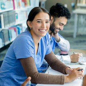 A female nursing student is taking notes in class.