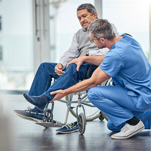 A physical therapist assists a patient in a wheelchair. A physical therapist assists a patient in a wheelchair.