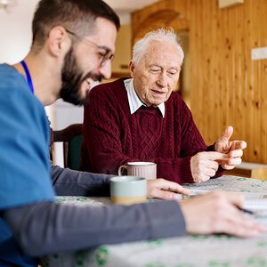An elderly man enjoys a coffee break with his caregiver. An elderly man enjoys a coffee break with his caregiver.