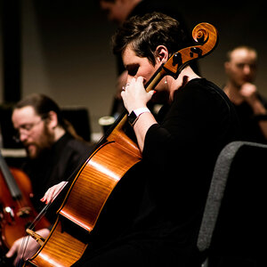 A cello player performing with an orchestra. A cello player performing with an orchestra.