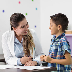 A child and a psychologist in a classroom. A child and a psychologist in a classroom.