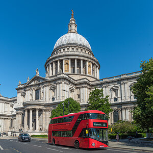A double-decker bus passes in front of the ornate façade of St. Paul’s Cathedral in London.