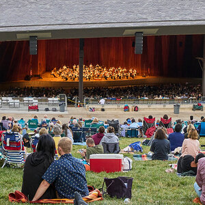 A large outdoor amphitheater full of people watching a concert.
