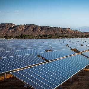 A large solar array in the desert with mountains in the background.