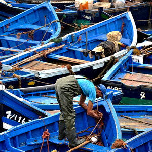 A man prepares equipment on a docked fishing boat.