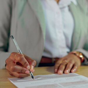 A person signing a letter. A person signing a letter.