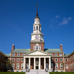 A red brick college building with a clock tower and Greek pediment under a deep blue sky – the Miller Library at Colby College. A red brick college building with a clock tower and Greek pediment under a deep blue sky – the Miller Library at Colby College.