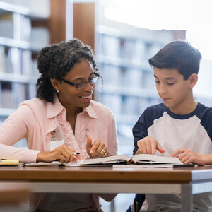 Female tutor sitting at table with male middle school student.