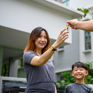 Smiling Asian American woman and young boy being handed keys.
