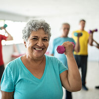 An older woman using free weights to exercise. An older woman using free weights to exercise.