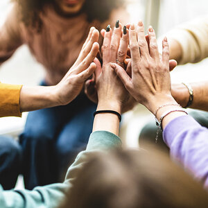 A group of hands joining together.