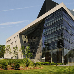 A modern glass medical school building surrounding by gardens.