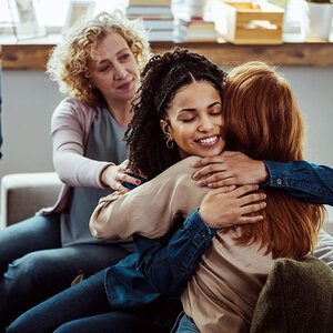 Two women hugging in a group meeting. Two women hugging in a group meeting.