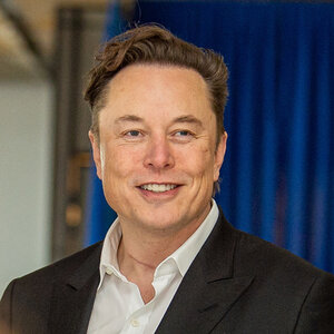 A businessman in a black suit jacket and white shirt – a photo of Elon Musk.