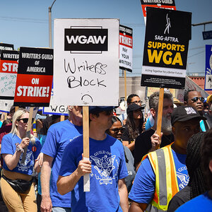 A group of striking workers on a picket line holding signs. A group of striking workers on a picket line holding signs.