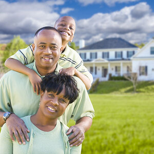 Black family of three standing in front of large home