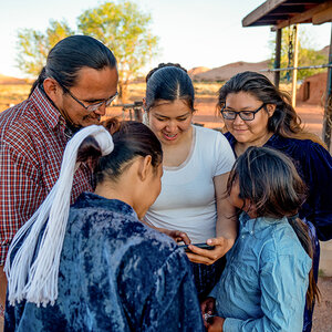 A group of Indigenous people talking over the news.
