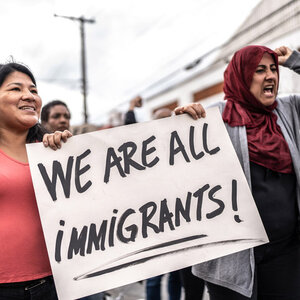 Two women at a protest hold a sign that reads, "We are all immigrants!"