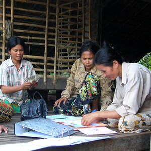 Three Cambodian women complete their accounting at a microfinance group meeting. Three Cambodian women complete their accounting at a microfinance group meeting.