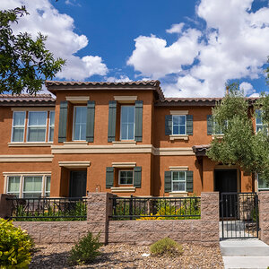 A row of new two-story homes surrounded by trees under a blue sky with clouds. A row of new two-story homes surrounded by trees under a blue sky with clouds.
