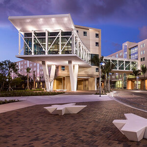 A white and brightly lit modern college campus building at night.