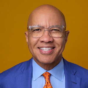 A bald man with glasses wearing a blue suit and orange tie - a photo of Darren Walker. A bald man with glasses wearing a blue suit and orange tie - a photo of Darren Walker.